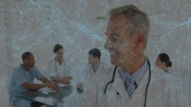 Tıbbi ekip toplantı odasında cam masanın etrafında dijital ağ örtüsünü gösteren verileri tartışıyor. Sağlık, takım çalışması, işbirliği, profesyonellik, yenilik, teşhis, danışma