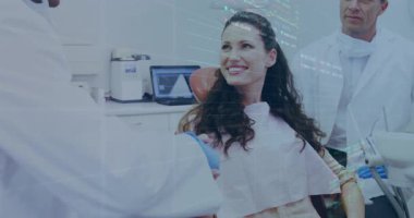 Hasta gülümsüyor ve dişçi muayenehanesine bakıyor, dişçiler aletleri yüzen veri grafikleriyle ayarlıyorlar. Diş sağlığı, sağlık, klinik, tıbbi, profesyonellik, temiz, fütüristik