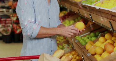 Turuncuyu tutan adam, üretim reyonundaki market teknolojisini araştırırken ikili kodları gösteriyor. Üretim, sağlıklı, dijital, modern, pazar, tazelik, yenilik