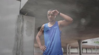 Üstgeçidin altında duran bir koşucu. Etrafına su sıçrıyor. Fitness teknisyeninin saatini vurguluyor. Atletik, hareketli, kentsel, fitness, teknoloji, motivasyonel, dinamik