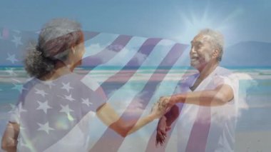 Son sınıf çifti kumlu sahilde dans ediyor. Grafik Amerikan bayrağı sergiliyorlar. Romantizm, kutlama, açık hava, seyahat, kaygısız, hayat dolu, neşeli