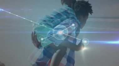 Kadın, sahil şeridine yakın bir yerde oğlanı sırtında taşıyor. Teknoloji ağı düğümleri gösteriyor. Aile, bağlantı, rahatlama, açık hava, dijital, gündelik, arkadaşlık