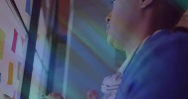 Ofisteki cam panoya bakan kadın, iş diyagramlarını izleyen adam ve yapışkan notlar. İşbirliği, beyin fırtınası, takım çalışması, yenilik, modernlik, profesyonellik, sunum