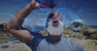 Kıdemli adam kayalık sahilde su şişesi tutuyor, devre grafikleri ve holografik halkaları gösteriyor. Atletik, yenilikçi, fütüristik, sağIık, manzara, teknoloji, canlılık