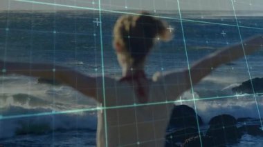 Okyanusa bakan kıyı şeridinde duran kadın, deniz mavisi şebekesiyle teknolojik görselleştirmeyi gösteriyor. Açık hava, macera, yenilik, fütürist, sükunet, esneklik, manzara