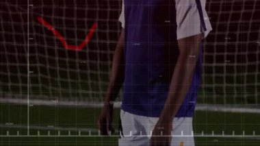 Erkek sporcu, kırmızı azalan grafiğini ve yüzen numaralarını göstererek futbol kalesi ağında duruyor. Sporcu, analitik, performans, dijital, spor, fütüristik, metrik