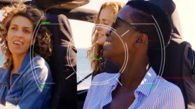 Üç arkadaş gülüyor ve üstü açık araba kullanıyor. Sahil yolunda HUD teknolojisi üst üste biniyor. Macera, açık hava, gençlik, coşku, seyahat, dostluk, özgürlük