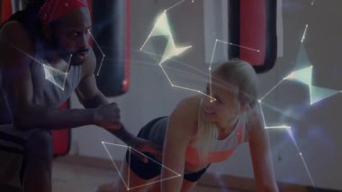 Spor salonunda kum torbasını yumruklayarak müşteri kalaslarını çalıştıran antrenör, ağ hatlı holografik küreyi gösteriyor. Fitness, antrenman, egzersiz, dijital, küresel, bağlantı, güç