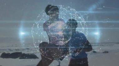 Sahilde teknolojiyi keşfeden erkek ve kadın, parlayan düğümlerle holografik küreyi manipüle ediyorlar. Gelecekçi, yenilikçi, bağlantı, dijital, rahatlama, açık hava, işbirliği