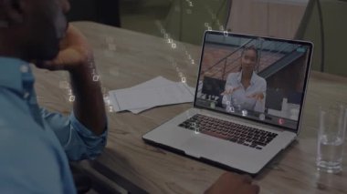 Mavi gömlekli bir adam laptopta iş görüşmesine katılıyor. Kağıtlar, su bardakları, ikili kod. Şirket, iletişim, çalışma alanı, profesyonellik, teknoloji, işbirliği, modern