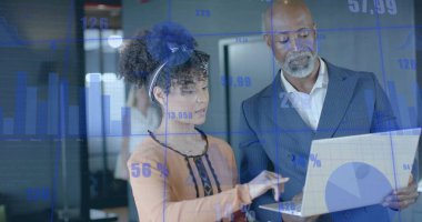 Şeftali rengi bluzlu bir kadın ofiste takım elbiseli, kulaklık takan bir adamla dizüstü bilgisayarın çizelgelerini inceliyor. İş, teknoloji, analitik, kurumsal, takım çalışması, modern, veri görselleştirme