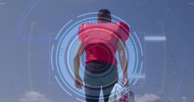 Kırmızı futbol formalı bir atlet açık alanda kaskını yan yana tutuyor ve HUD kaplamalı. Atlet, spor giyim, fütüristik, dijital, açık hava, performans, egzersiz