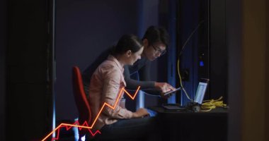 Tablet kullanan kadın ve meslektaş eğilip neon grafikleri ve sarı kabloları izliyorlar. İşbirliği, teknoloji, veri, yenilik, çalışma alanı, modern iletişim