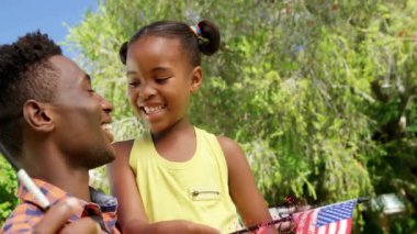 Baba ve kızı bahçede bayrakları tutarken, animasyon toz parçacıkları pazarlama için dağılıyor. Aile, kutlama, açık hava, canlı, neşeli, bağlanma, toplum