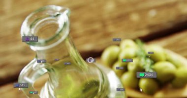 Cam zeytin yağı şişesi tahta kaşığın yanında duruyor zeytin ve sosyal medya ikonları havada süzülüyor. Gurme, aşçı, köylü, minimalist, sağlık, organik, doğal