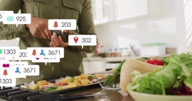 Ev aşçısı kadın mutfak tezgahında akıllı telefon dinliyor, pazarlama ölçülerini gösteriyor. Aşçılık, teknoloji, sosyal medya, modern, yaşam tarzı, katılım, sağlık