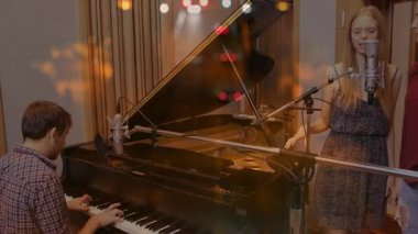 Büyük piyano çalan adam ve kayıt stüdyosunda şarkı söyleyen kadın, yüzen ses dalgaları gösteriyor. Müzik, stüdyo, akustik, işbirliği, performans, kayıt, sağlık