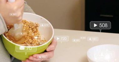 Kadın tezgahta granola karıştırıyor, yüzen sosyal medya pazarlama ölçümleri gösteriyor. Sağlık, sağlık, beslenme, yemek pişirme, yerli, köylü, canlı