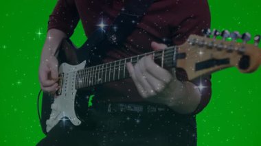 Parıltıların müzik teknolojisini tanıttığı, yeşil arka planda siyah gitar tıngırdatan müzisyen. Kaya, performans, canlı, dinamik, enerji, eğlence, yaratıcılık