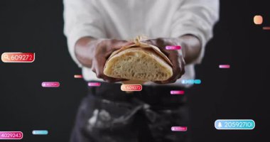 Yiyecek pazarlamada kabuklu ekmek tutan bir adam. Karanlık zeminde yüzen bildirim rozetleri gösteriyor. Esnaf, aşçı, markalaştırma, dijital, canlı, modern, gurme