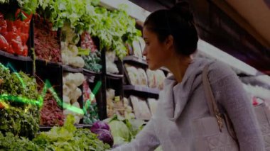 Süpermarkette yapraklı yeşilliklere uzanan bir kadın perakende analizi için yeşil çizgi grafiği gösteriyor. Sağlıklı, organik, perakende, ticaret, görsel, taze, tüketici
