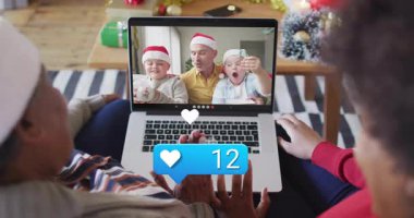 Büyükanne ve kızı dizüstü bilgisayarlarını kullanarak yüzen kalplerle sanal tatil çağrısına katılıyorlar. Şenlik, aile, kutlama, teknoloji, sıcaklık, bağlantı, konforlu