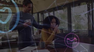 Ofiste dizüstü bilgisayarda yazan profesyonel bir kadın, elinde kahve tutan bir adam, yüzen teknoloji ikonları. İşbirliği, uzaktan çalışma, dijital iletişim, ağ, konfor, üretkenlik, modern