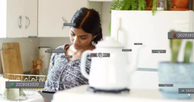 Mutfakta tablet okuyan bir kadın, yüzen kimlikler ve simgelerle üstüste binen teknolojileri gösteriyor. Modern, yaşam tarzı, minimalist, dijital, samimi, yerli, yenilikçi