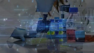 Laboratuvar bilimcisi çok kanallı pipet kullanıyor. Sıvıyı çok katmanlı plakaya yerleştiriyor. Veri örtülü. Laboratuvar, bilim, araştırma, kesinlik, enstrümantasyon, veri, teknoloji