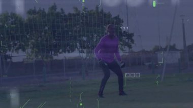 Spor antrenman sahasında duran genç erkek kaleci, dijital ikon ve istatistikleri gösteriyor. Atletik, açık hava, spor, dijital, rekabetçi, enerji, modern