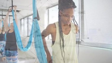 İki kadın spor salonundaki mavi yoga hamaklarını ayarlıyor, çizelgeler ve ağ şemaları sergiliyorlar. Zindelik, sağlık, siluet, şehir, dekor, canlılık, konsantrasyon