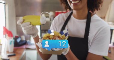 Yemek satıcısı seyyar mutfakta sosisli hazırlıyor, hardal damlaları ve kırmızı bardaklar sergiliyor. Sokak yemekleri, aşçılık, coşku, konukseverlik, sokak satıcısı, hızlı gündelik, renkli