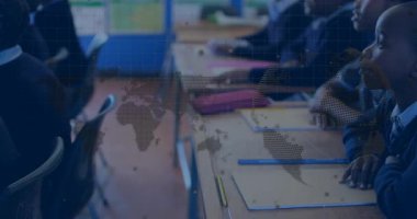 İlkokul çocukları masalarında işaretler olan manzaralar çiziyor, saydam dünya haritası örtüşüyor. Eğitim, yaratıcılık, işbirliği, çocukluk, öğrenme, sanatsal, sınıf