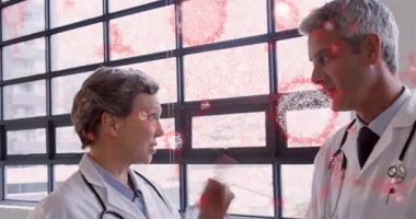 Klinikte bilgi alışverişinde bulunan iki tıp uzmanı, pencerede kırmızı hücre kaplaması gösteriyor. Sağlık, takım çalışması, teşhis, laboratuvar, klinik, araştırma, işbirliği
