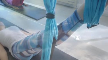 Yoga minderinde uzanan kadın spor yaparken spor salonunda canlı yayın simgeleri sergiliyor. Sağlık, zindelik, hareket, rahatlama, teknoloji, bağlantı, sağlık