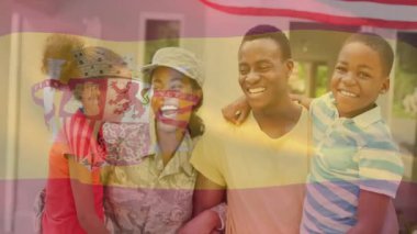 Evin önünde duran aile, yarı şeffaf bayrak kaplamalı İspanyolca öğreniyor. Aile, ev, birlik, çeşitlilik, vatanseverlik, kutlama, açık hava