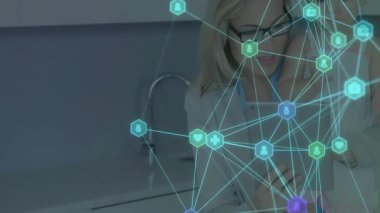 Mutfakta tablet kullanan, parıldayan sağlık ve güvenlik ağı simgeleri gösteren bir kadın. Aile, bağlantı, teknoloji, güvenlik, ebeveynlik, bakım, modern