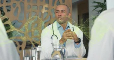 Toplantıda oturan erkek doktor, steteskop ve sürahi üzerinde yüzen tıbbi raporlar gösteriyor. Profesyonel, işbirliği, şirket, danışma, sağlık, modern, takım çalışması