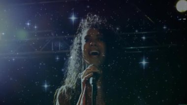 Mikrofon müzik sahnesini çeken kadın şarkıcı, yıldız figürleri ve kozmik ışıklandırma efektleri sergiliyor. Performans, müzik, eğlence, canlı, anlamlı, gece, dinamik