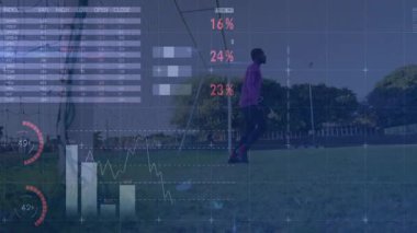 Erkek sporcu, futbol sahasında çömelmiş yüzen grafiklerle spor verilerini sergiliyor. Sporcu, yarışma, analiz, dijital, görselleştirme, açık hava, fitness