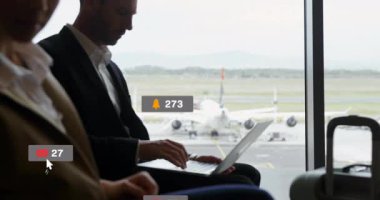 Havaalanı salonundaki iş ikilisi pazarlama için yüzen medya simgeleriyle akıllı telefon ve dizüstü bilgisayar kullanıyor. Teknoloji, iletişim, işbirliği, modern, profesyonel, seyahat, dijital