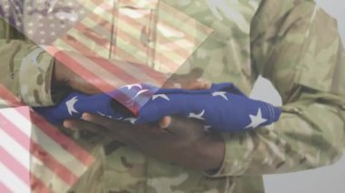 Kamuflaj üniformalı erkek asker Amerikan bayrağını çizgili tutuyor, eğitim sunuyor. Askeri, vatanseverlik, disiplin, kahramanlık, yiğitlik, güç, dayanıklılık