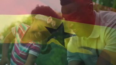 Baba ve kızı arka bahçede oynuyorlar, şeffaf Gana bayrağıyla pazarlama tasarımı gösteriyorlar. Aile, açık hava, neşe, kaynaşma, manzara, kutlama