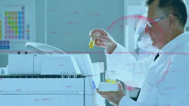 Kıdemli bilim adamı test tüpünü kaldırarak analiz için sarı örnekleri yükleyen laboratuvar analizcisini tetikledi. Laboratuvar, araştırma, enstrümantasyon, bilim, yenilik, teknoloji, profesyonel