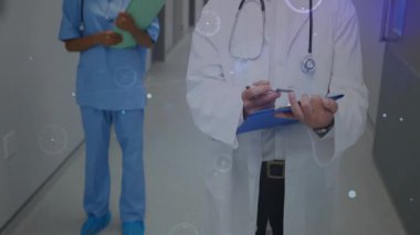 Kamera, doktor yazılarını gösteriyor. Tıbbi veriler toplanırken hemşire çizelgesini tutuyor. Tıbbi, klinik, sağlık, teknoloji, işbirliği, yenilik, dijital