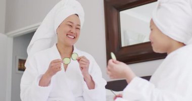 Mutlu Asyalı anne ve kızının salatalık maskesi takıp eğlendiği bir video. Aile, annelik, ilişkiler ve birlikte kaliteli zaman geçirme konsepti dijital olarak oluşturulmuş video.