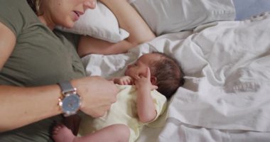 Yeni doğmuş bir bebekle yatakta oynayan mutlu bir beyaz annenin videosu. annelik, ebeveyn sevgisi ve yeni doğan bebek konseptiyle ilgilenmek dijital olarak üretilmiş video.