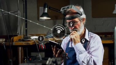 Üst düzey adam akıllı telefonu dinliyor ve atölye tezgahlarında dijital ağ simgelerini görselleştiriyor. Teknoloji, yenilik, işçilik, bağlantı, dijital, çalışma alanı, yaş