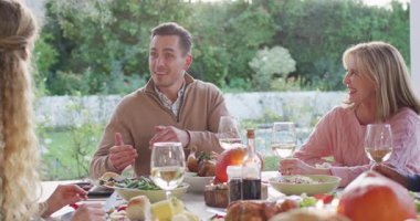 Video of happy caucasian father telling story at outdoor family dinner table. Family, domestic life and togetherness concept digitally generated video.