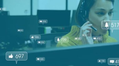 Ofis görevlisinin kulaklığı ayarlaması ve bölmelerde konuşması UI baloncuklarının nişan sayılarını güncellemesi. İşbirliği, iletişim, üretkenlik, teknoloji, takım çalışması, modern, dijital